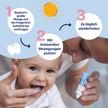 Mutter die einem Baby die Kauleisten massiert und die Tube Dentinox Zahncreme Mundflora Baby in der Hand hält, Blauer Balken mit weißen Kreis und Text sowie illustrierter Sonne