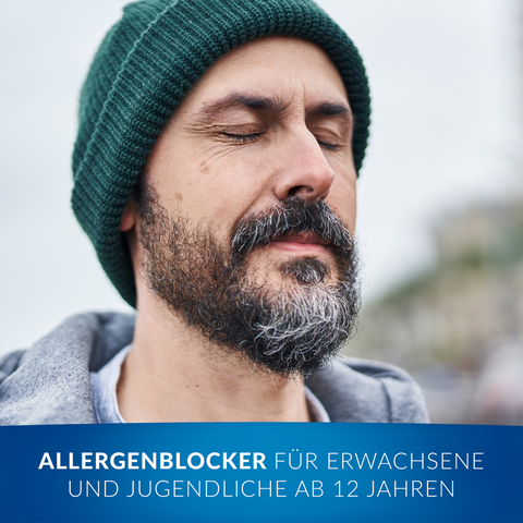 Durchatmender Mann mit Mütze, im Vordergrund Balken mit Schrift