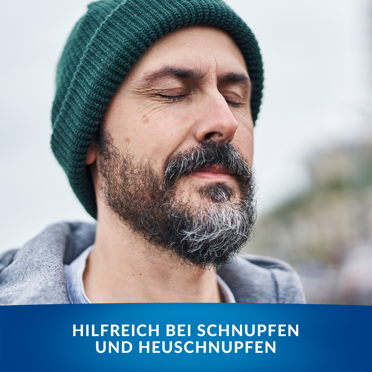 Durchatmender Mann mit Mütze, im Vordergrund Balken mit Schrift