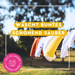 Wäsche wehend im Wind unter weißem Rahmen und Schrift auf gelben Balken