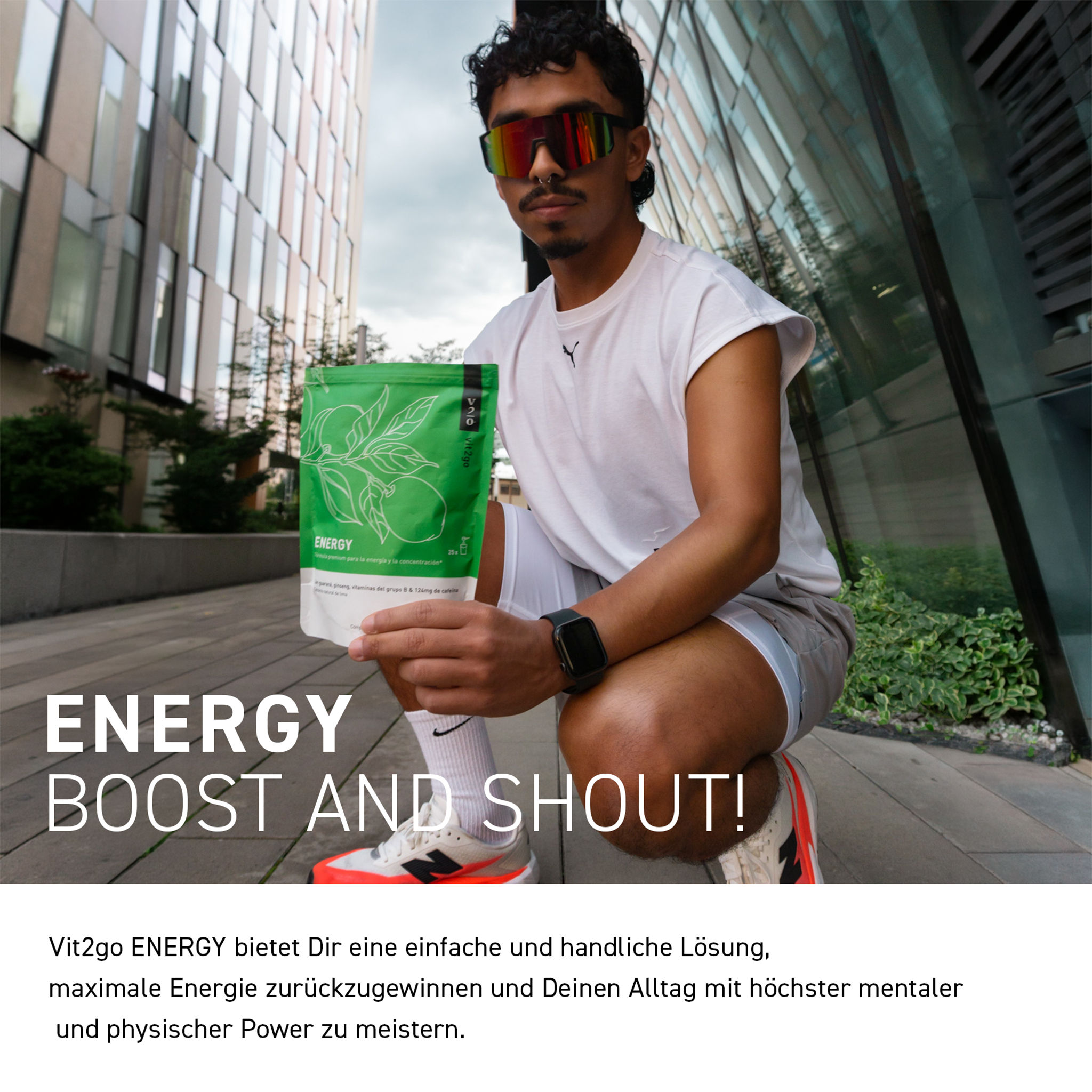 Mann im weißen Sportoutfit im Urban Setting mit  Vit2go Energy - 250g Standbeutel in der Hand, Schrift auf Bild und weißem Balken im Vordergrund
