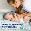 Frau cremt Bauch von Baby auf Decke ein, Text und Produkt im Vordergrund