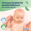 Baby mit Creme-Smiley auf der Brust und Händchen haltend mit einer Erwachsenen Person auf Decke, Schrift und Siegel im Vordergrund