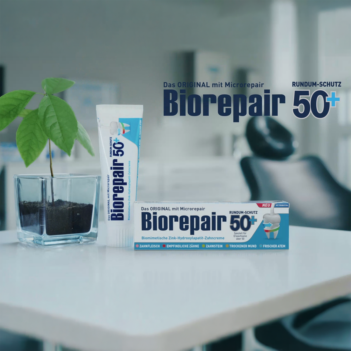 Biorepair Zahncreme Complete Protection 50 + – 12x75ml Tube und Verpackung auf Tisch neben Pflanze im Praxiszimmer
