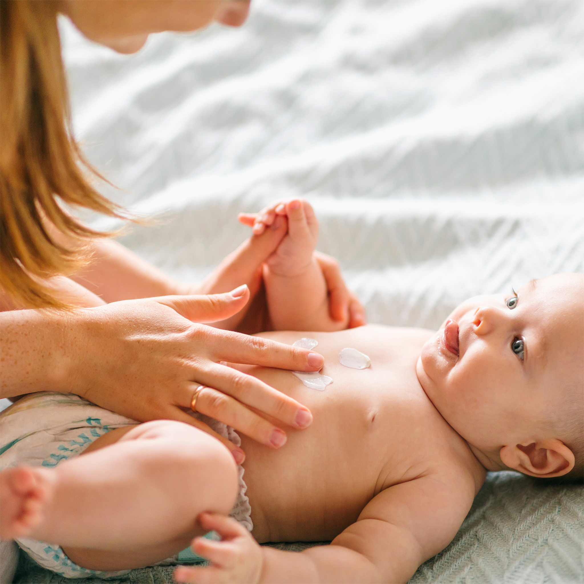Frau cremt Baby Bäuchlein ein