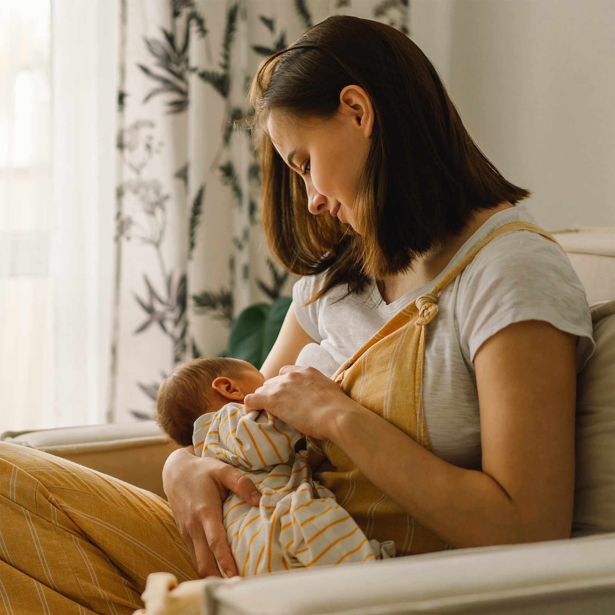 Frau stillt Baby auf Sessel