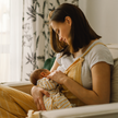 Frau stillt Baby auf Sessel