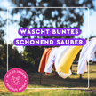 Wäsche wehend im Wind unter weißem Rahmen und Schrift auf lilafarbenen Balken