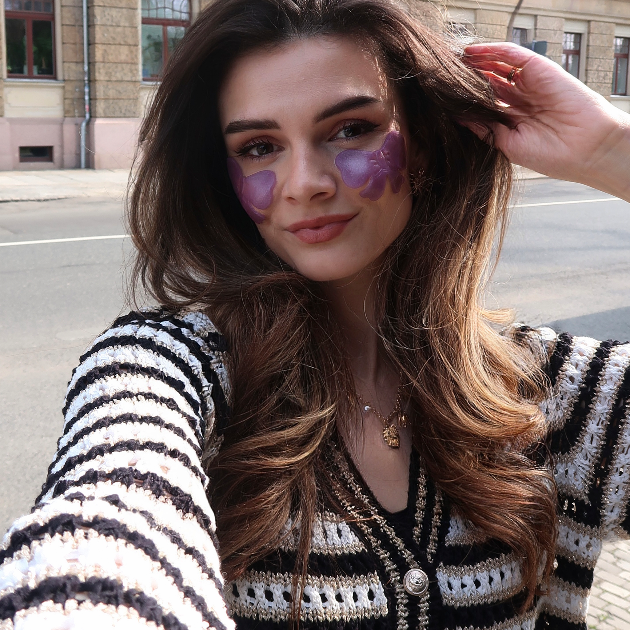 Frau trägt YEAUTY Emily in Paris Eye Pad Mask Bakuchiol Bow und streicht sich durchs Haar