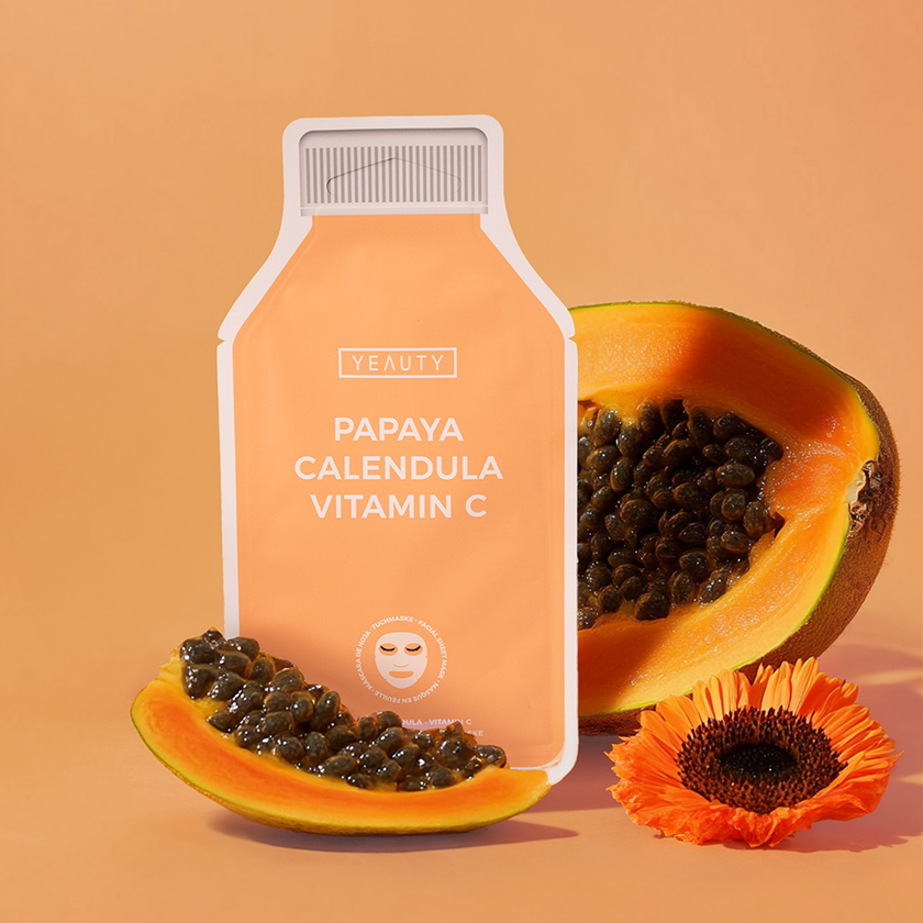 YEAUTY Tuchmaske Papaya Calendula Vitamin C zwischen Papaya und Calendula vor orangem Hintergrund