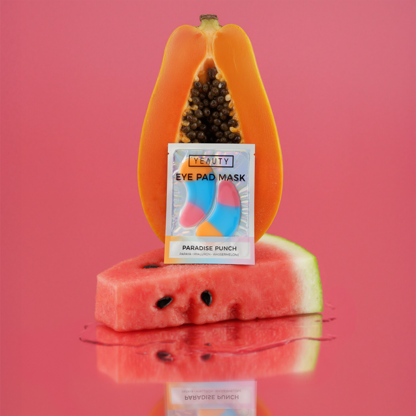YEAUTY Eye Pad Mask Paradise Punch auf Melonenstück, vor Papaya Hälfte mit pinkem Hintergrund