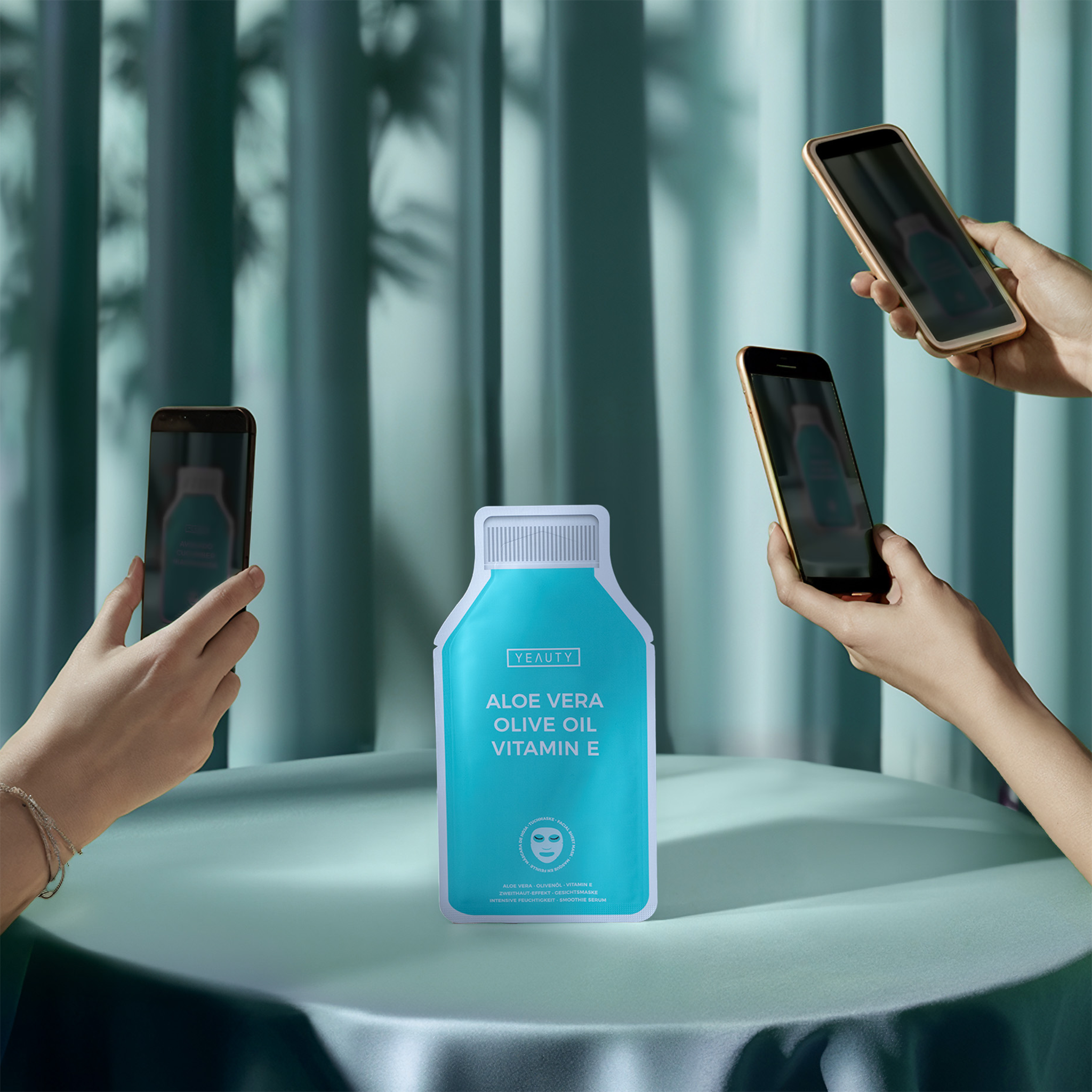 YEAUTY Tuchmaske Aloe Vera Olive Oil Vitamin E auf Tisch wird fotografiert von Handys