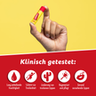 Siegel von Carmex Classic Stick auf rotem Grund und Hand die Carmex Classic Stick hochhält