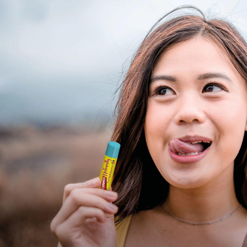 Carmex Naturally Stick Beere - Frau leckt sich über die Zunge