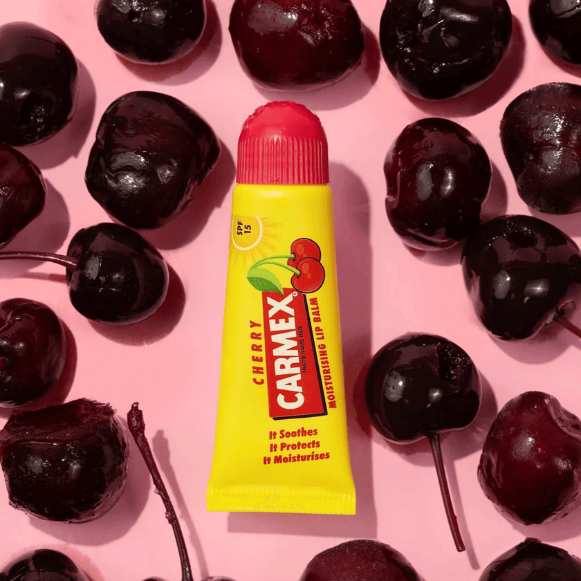 Carmex Kirsche Tube auf Kirschen und pinken Hintergrund