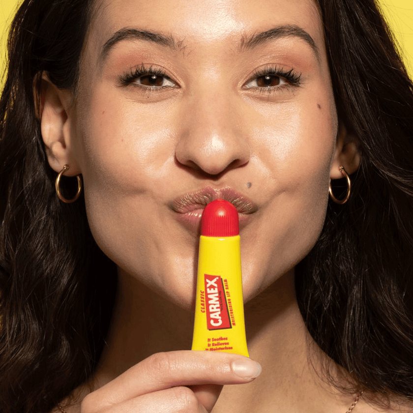 Frau küsst geschlossene Carmex Classic Tube