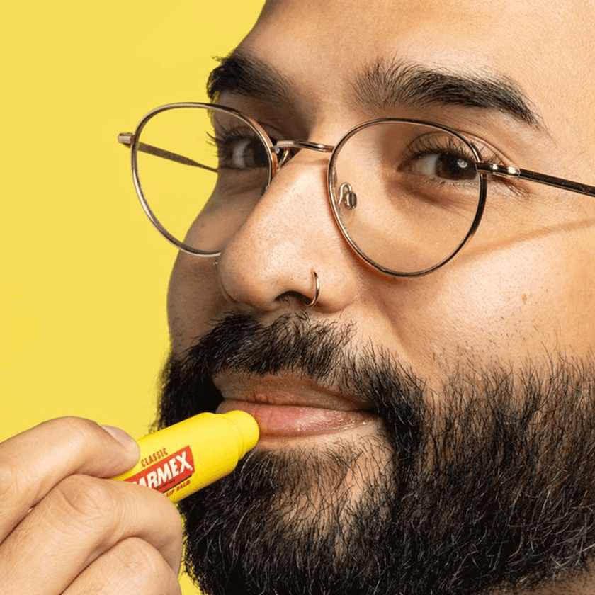 Mann trägt Carmex Classic aus der Tube auf seine Lippen auf